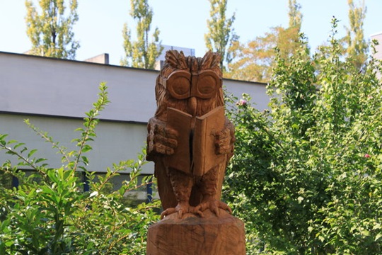 geschnitzte Holzeule mit einem Buch in den Händen